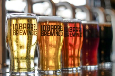 Five glasses of different colored beer from 10 Barrel Brewing Co. lined up on a reflective surface near LOCAL Boise apartments.