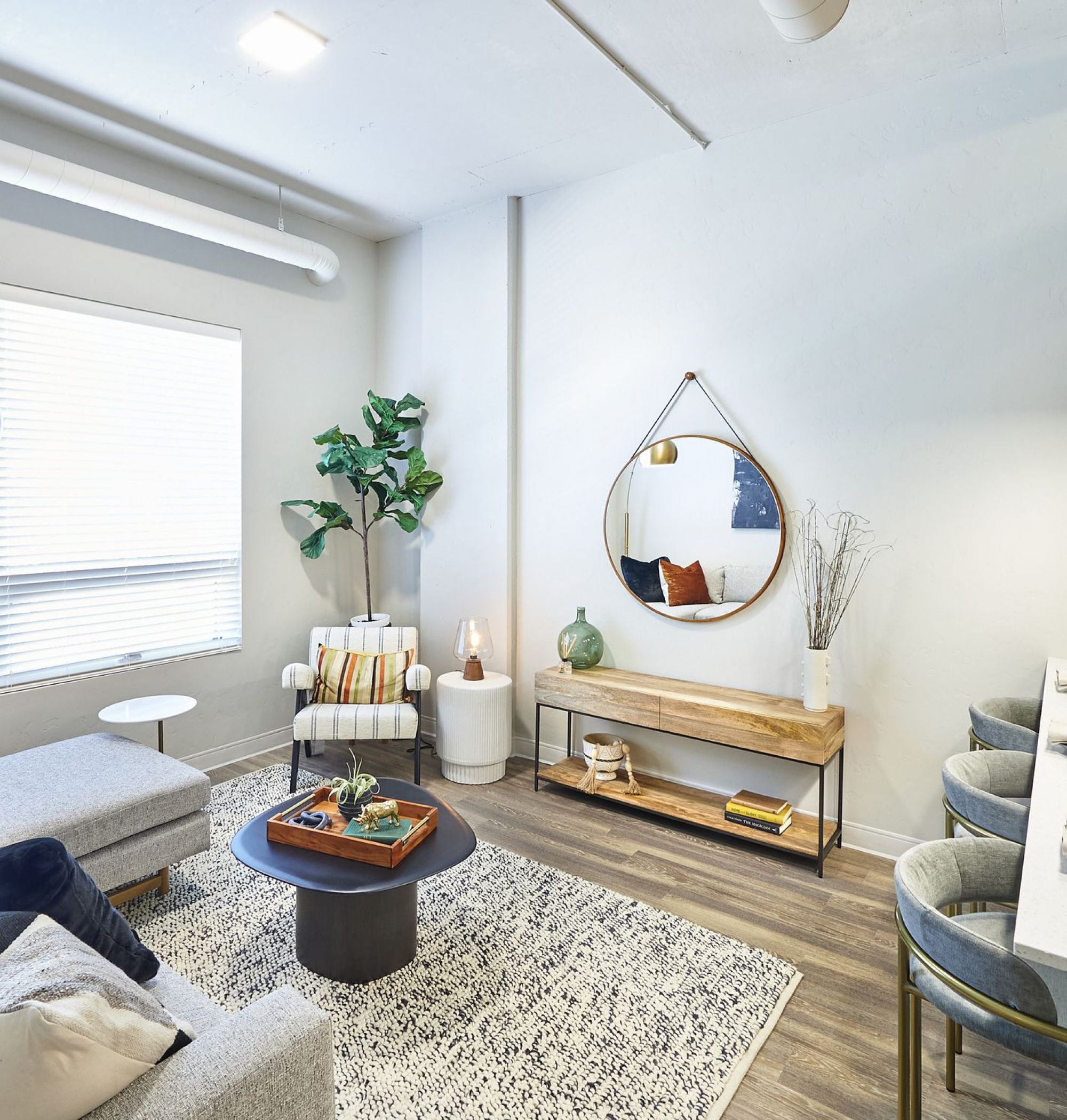 LOCAL Boise Apartments open floor plan living room and kitchen with large windows, roller shades, recessed lighting, and modern furnishings